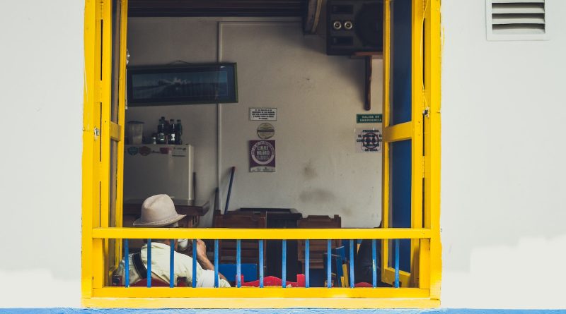 man sitting near window wearing cowboy hat